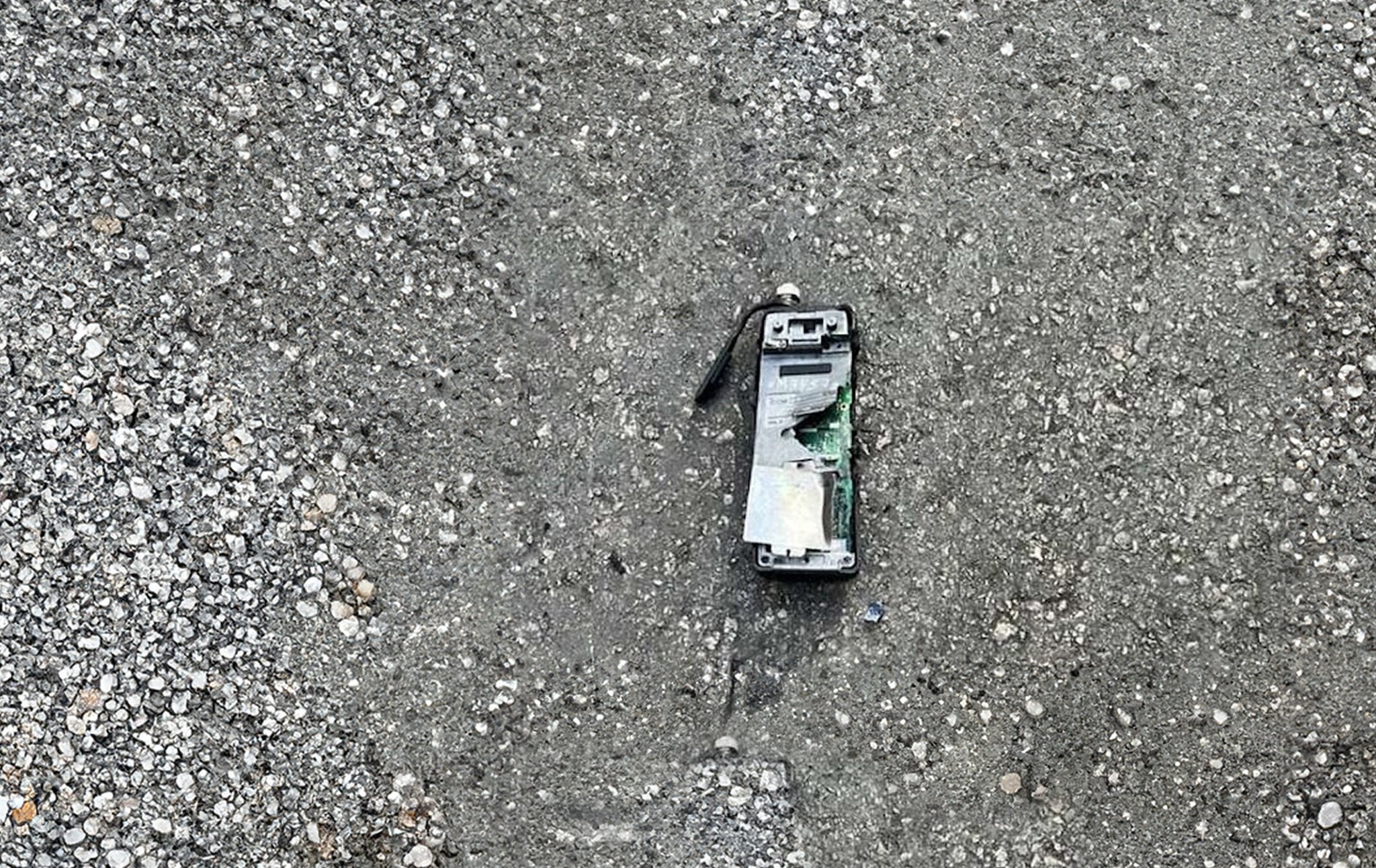 A broken and scorched pager lies on the pavement. It has clearly exploded recently.